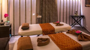 Relax in a serene spa room with two massage tables, a vase of flowers, and a peaceful ambiance.