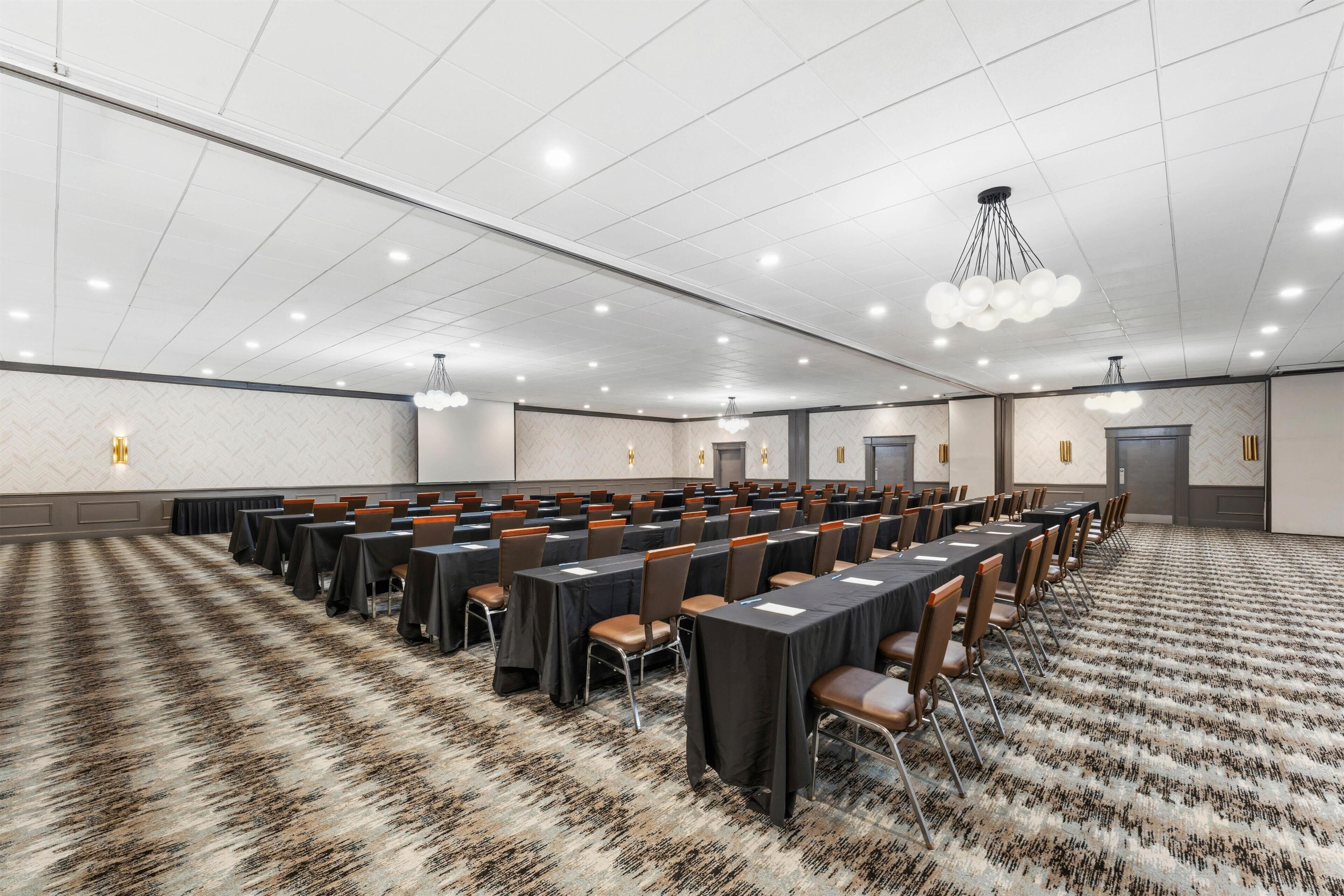 A conference room with multiple tables and chairs, a patterned carpet, and a modern ceiling design.