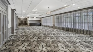 A hotel corridor with a patterned carpet, a long reception desk, and a row of windows with sheer curtains. - DoubleTree by Hilton Hotel Wilmington (Wilmington)