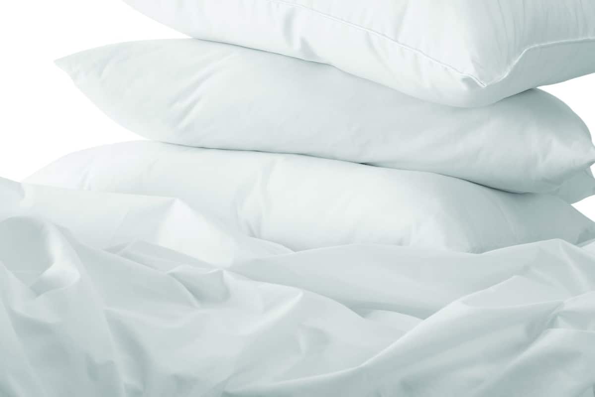 Une pile d’oreillers blancs sur un lit recouvert d’un drap blanc.