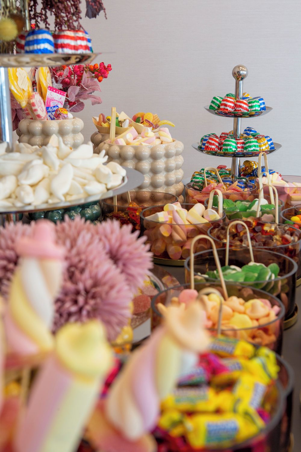 A variety of food items displayed on a buffet table, including pastries, candies, and other snacks.