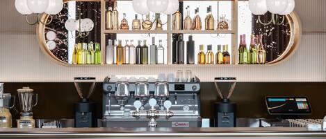Un área de bar con una máquina de café, una pantalla digital y estantes llenos de botellas de licores.