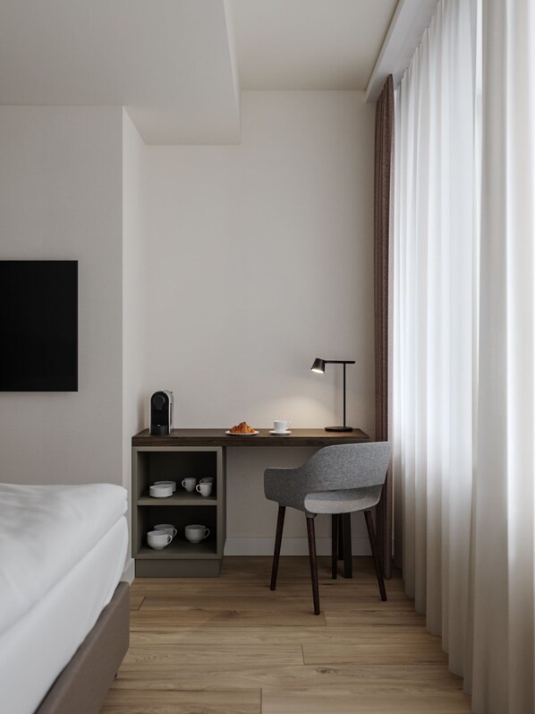 Una habitación de hotel moderna con cama, escritorio con silla, cafetera y televisor montado en la pared.