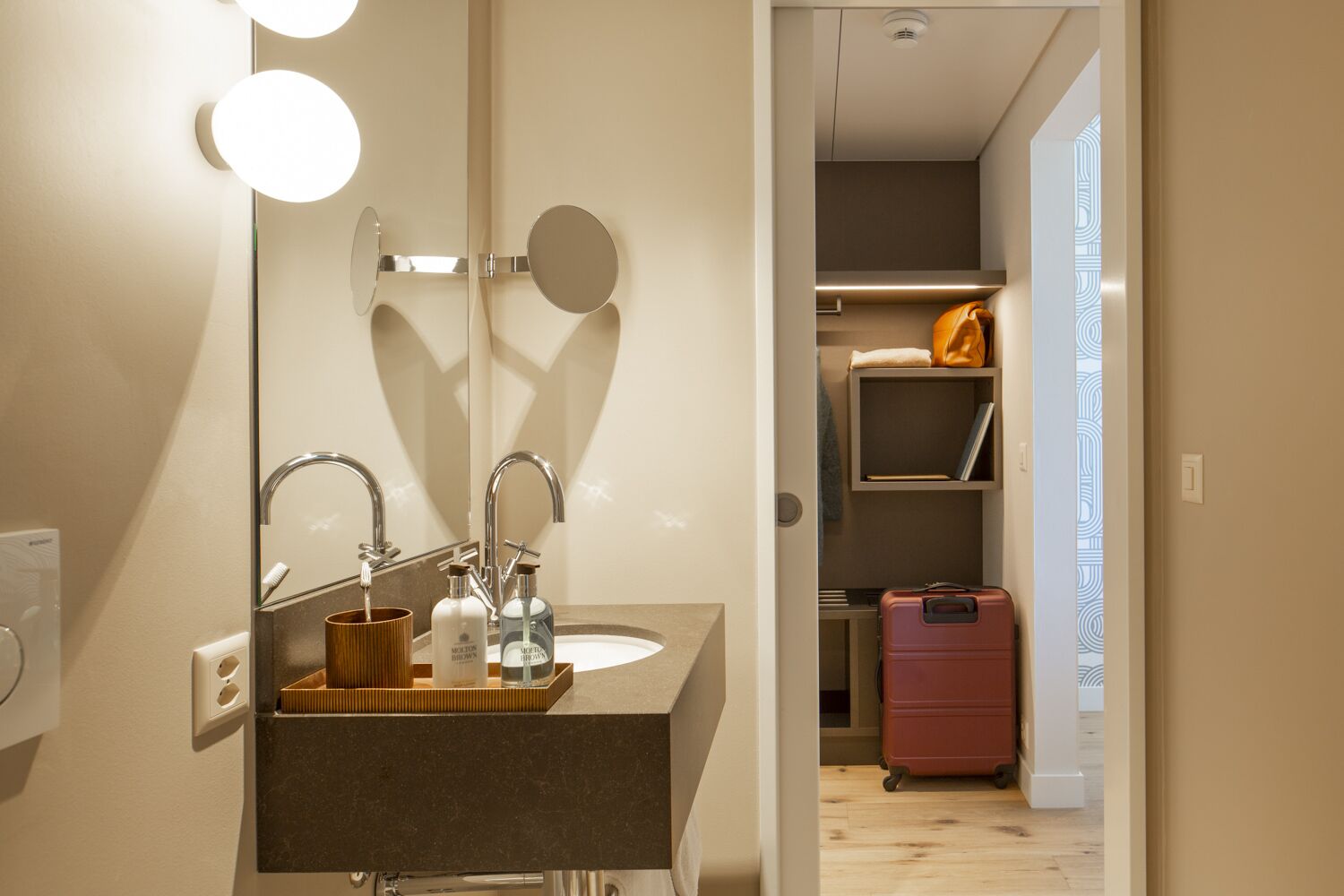 A modern bathroom with a vanity, mirror, and built-in shelves.