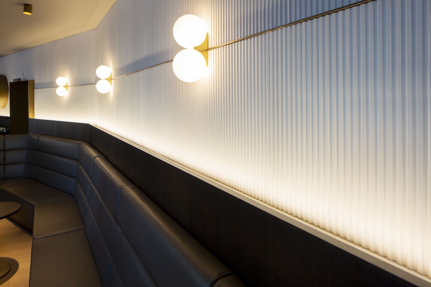 A modern interior with a curved bench seating area and a wall with vertical lines.