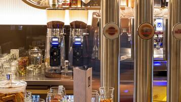 Un espace bar équipé de plusieurs distributeurs de boissons alcoolisées, d’une machine à café et d’une variété de bouteilles disposées en arrière-plan.