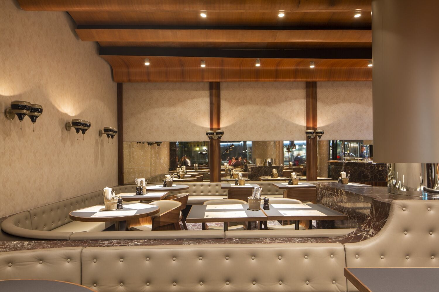 Een restaurant met hoge rugleunstoelen, ronde tafels en een bar.