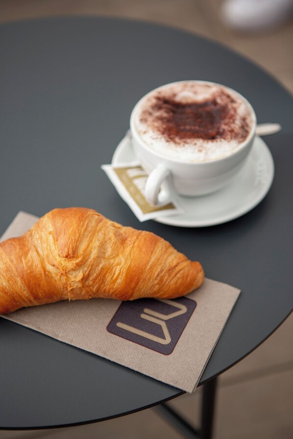 Un croissant y una taza de café sobre una mesa.