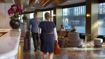 A modern lobby with a marble reception desk, seating areas, and large windows.