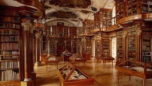 Una biblioteca imponente con techos altos, elaborados trabajos de madera y extensas colecciones de libros.