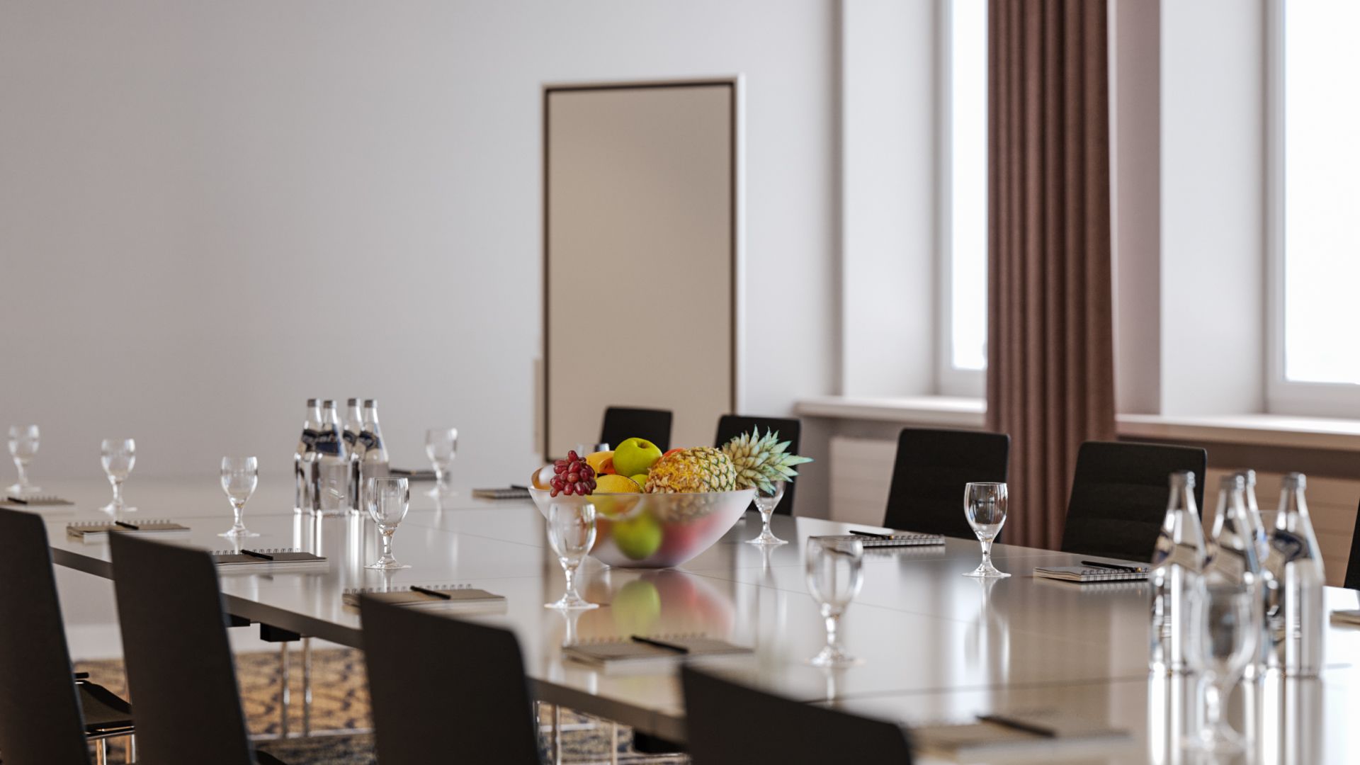 A conference room with a long table, chairs, a bowl of fruit, and water bottles.