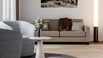 Una sala de estar moderna con un sofá gris, una mesa redonda de centro con un jarrón de flores y una fotografía grande enmarcada en la pared.