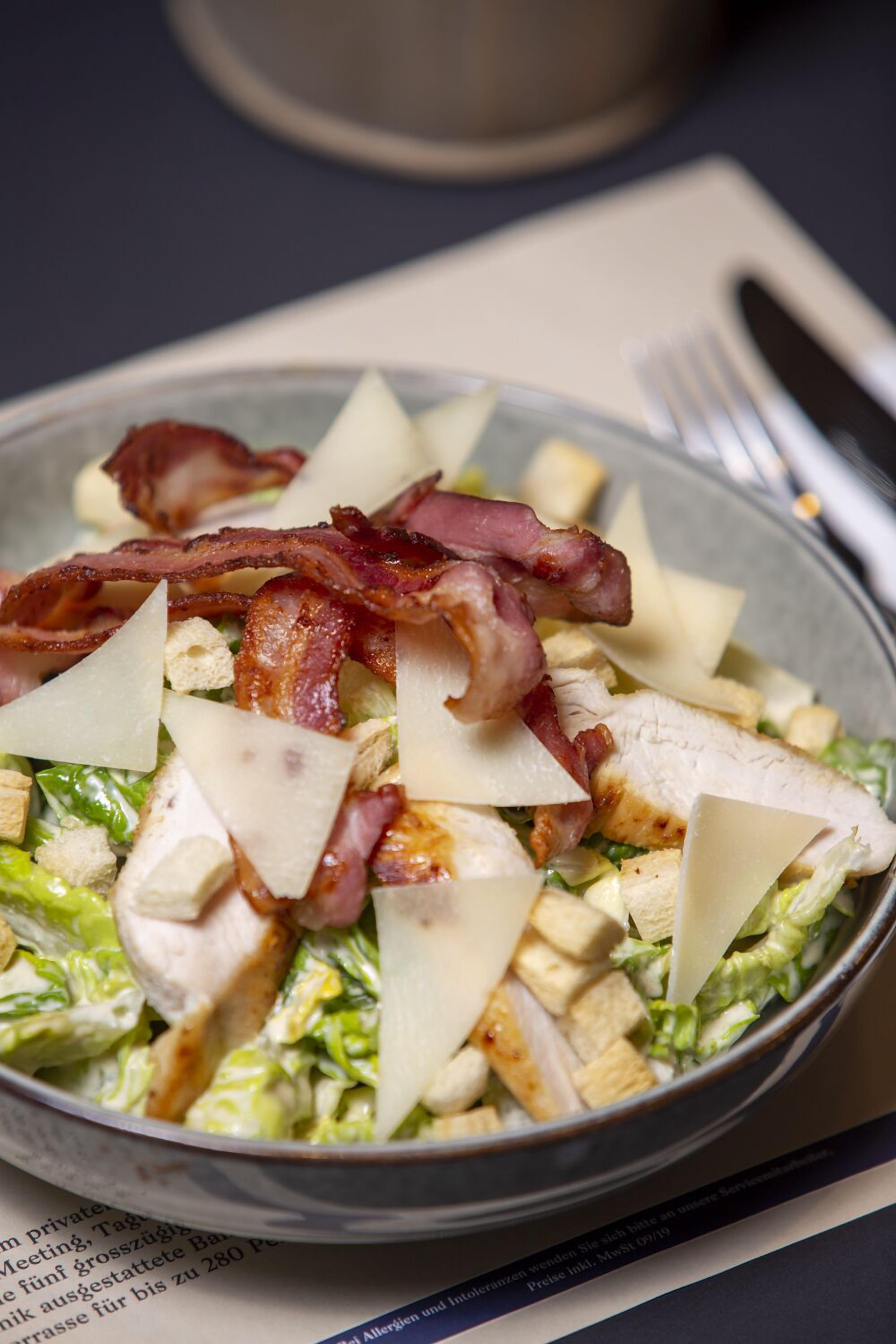 A bowl of salad with lettuce, chicken, cheese, and bacon.