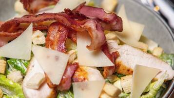 A bowl of salad with lettuce, chicken, cheese, and bacon.