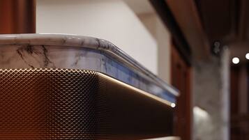 A marble countertop with a metallic object, possibly a speaker, and a textured surface.