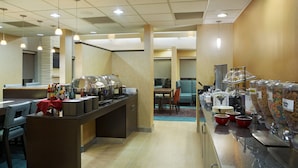 A hotel breakfast area with a buffet setup, including a counter with food items and a seating area with tables and chairs. - Residence Inn by Marriott San Antonio Downtown Market Square (San Antonio)