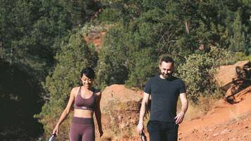 Two people walking on a rocky path with a mountainous backdrop.