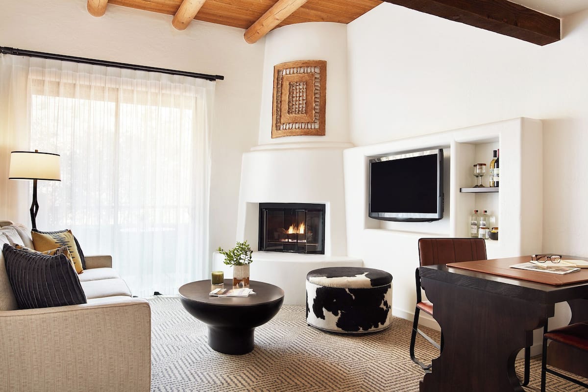 A modern living room with a fireplace, a flat-screen TV, a dining table, and a sofa.