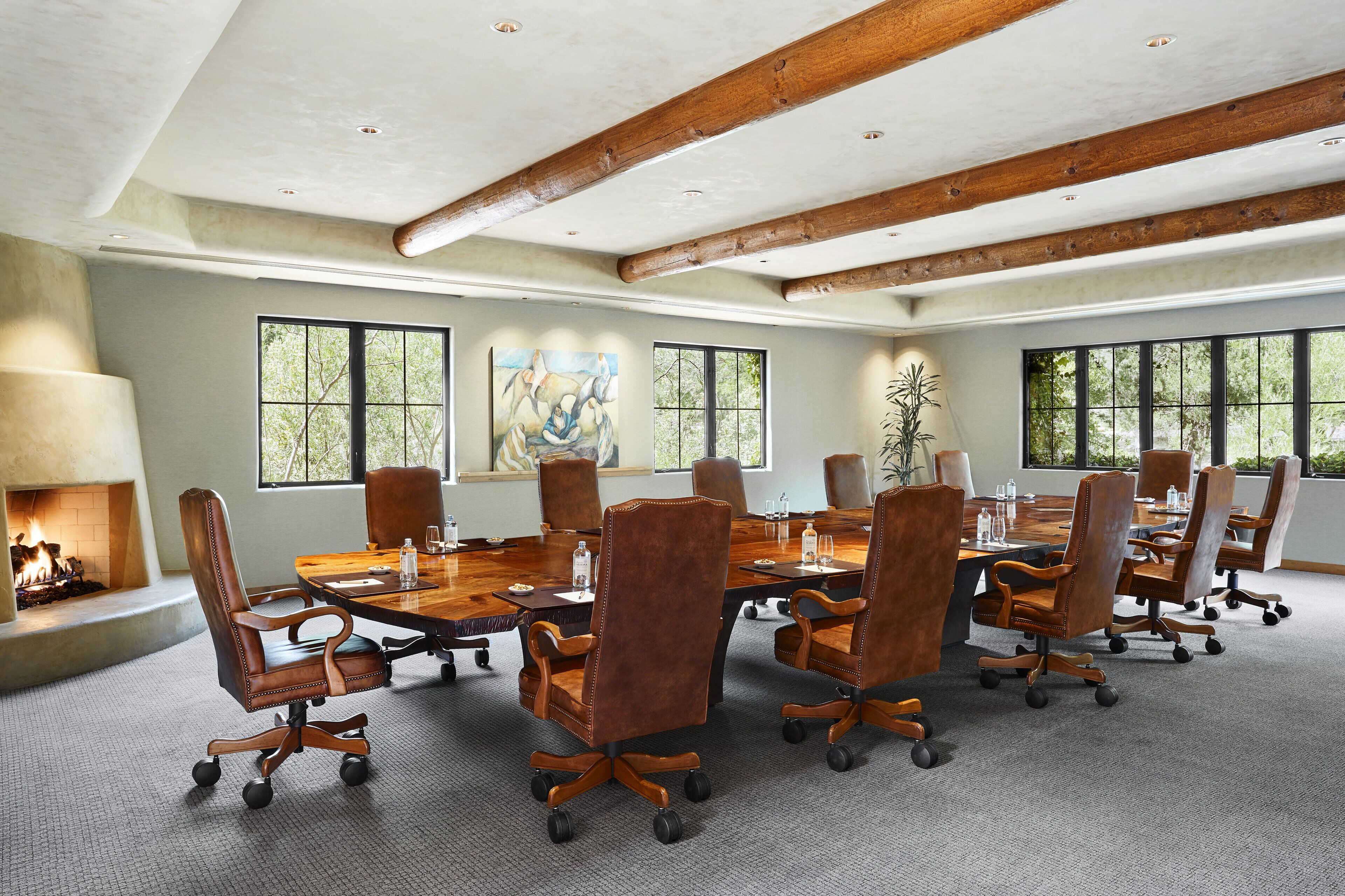 Une salle de conférence dotée d’une grande table en bois, de fauteuils en cuir et d’une cheminée.