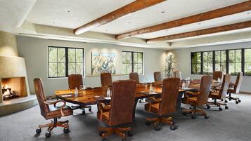 Une salle de conférence dotée d’une grande table en bois, de fauteuils en cuir et d’une cheminée.