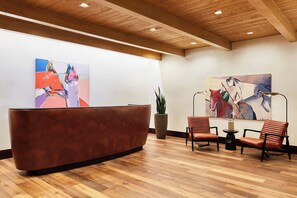 A reception area with a wooden reception desk, two leather chairs, and abstract paintings on the walls. - Enchantment (Sedona)
