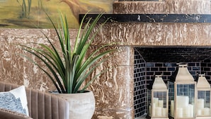 Un vestíbulo con un gran mural, una chimenea con velas, una planta en maceta y una zona de estar.