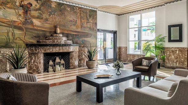 Un vestíbulo con un mural grande, una chimenea, zona de estar y ventanas amplias.
