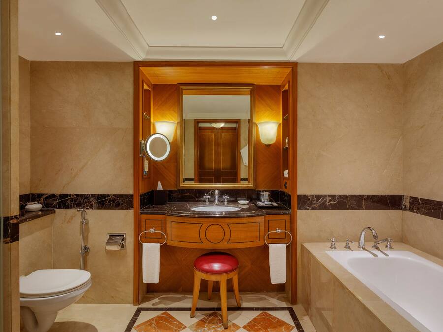 A modern bathroom with a marble vanity, a bathtub, and a toilet.