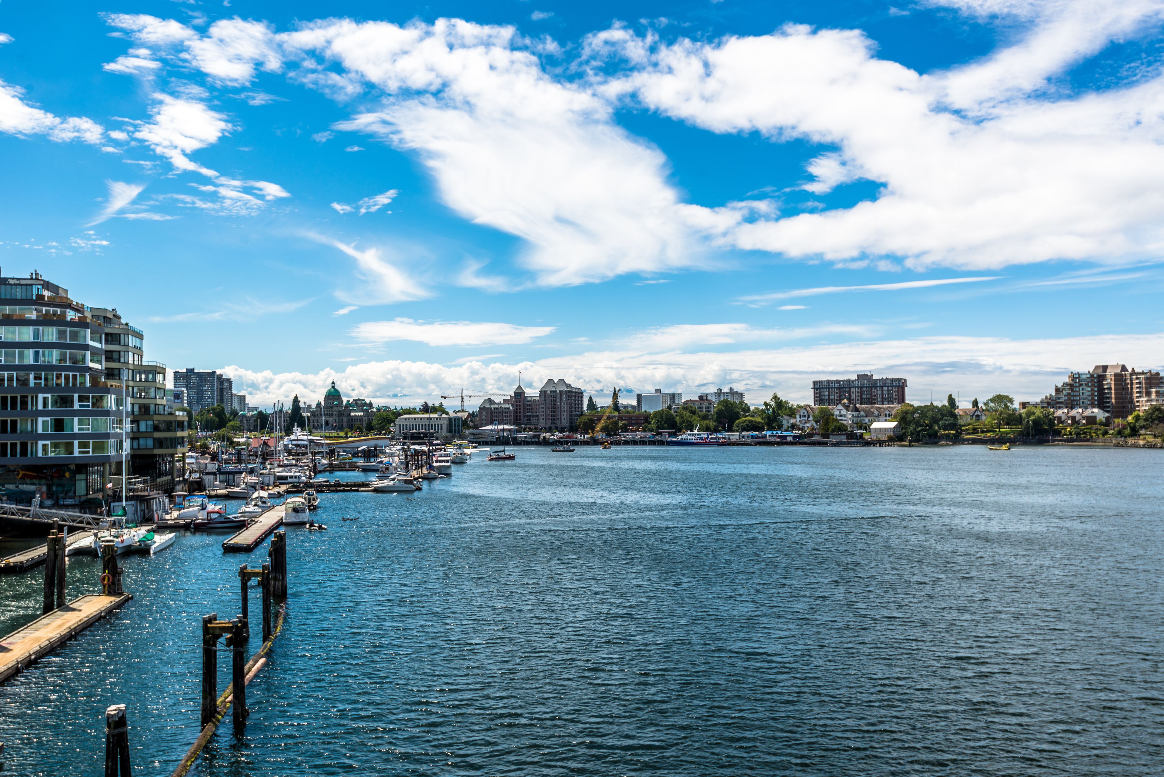 A marina with boats docked, a pier, and buildings in the background.