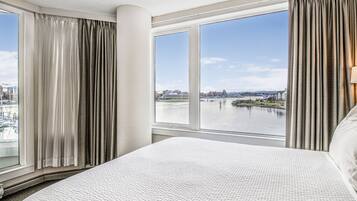 Een hotelkamer met een groot bed, uitzicht op een rivier en een stadsbeeld op de achtergrond.