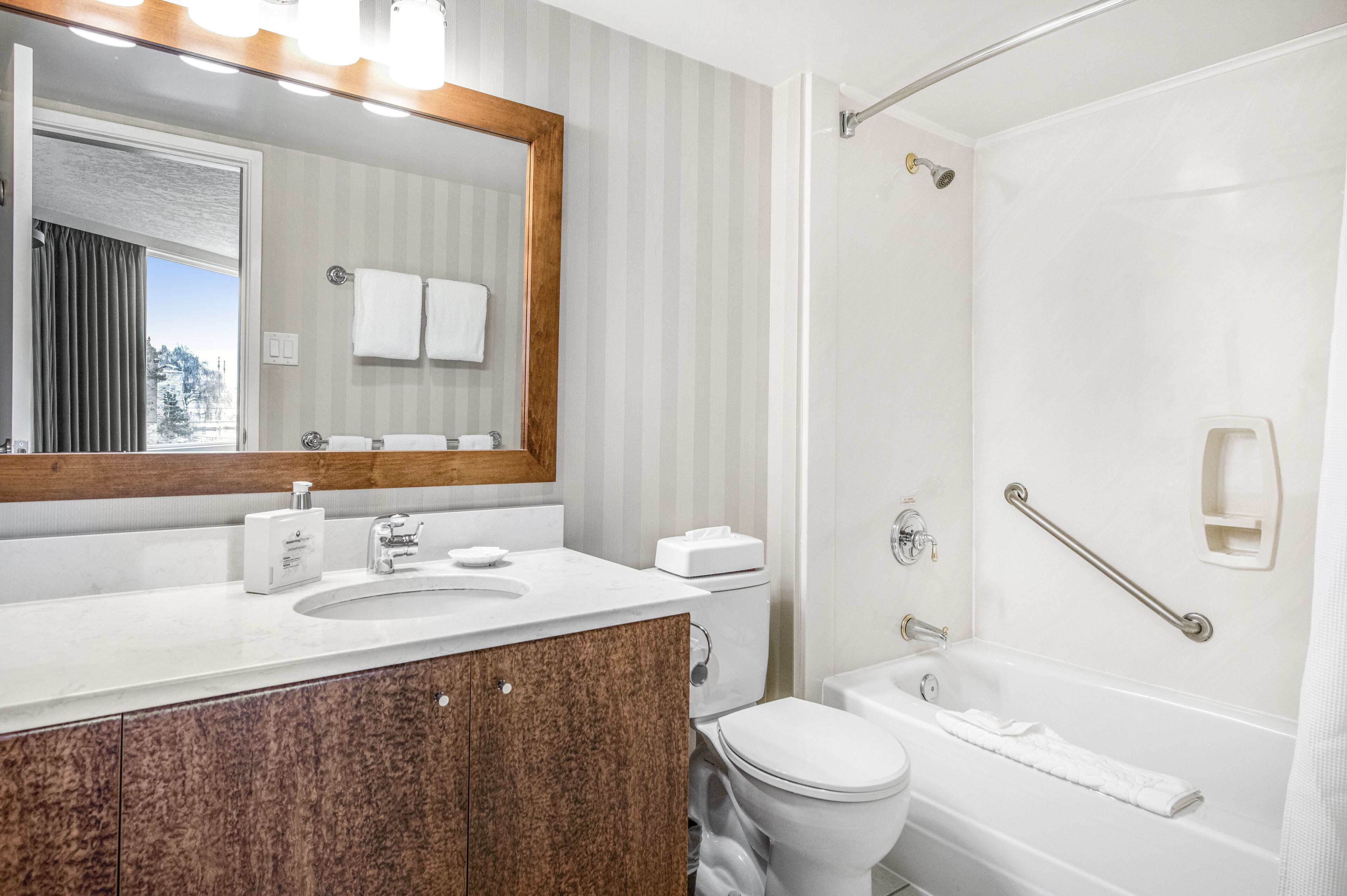 Un baño moderno con un espejo grande, un lavamanos, un inodoro y una bañera.