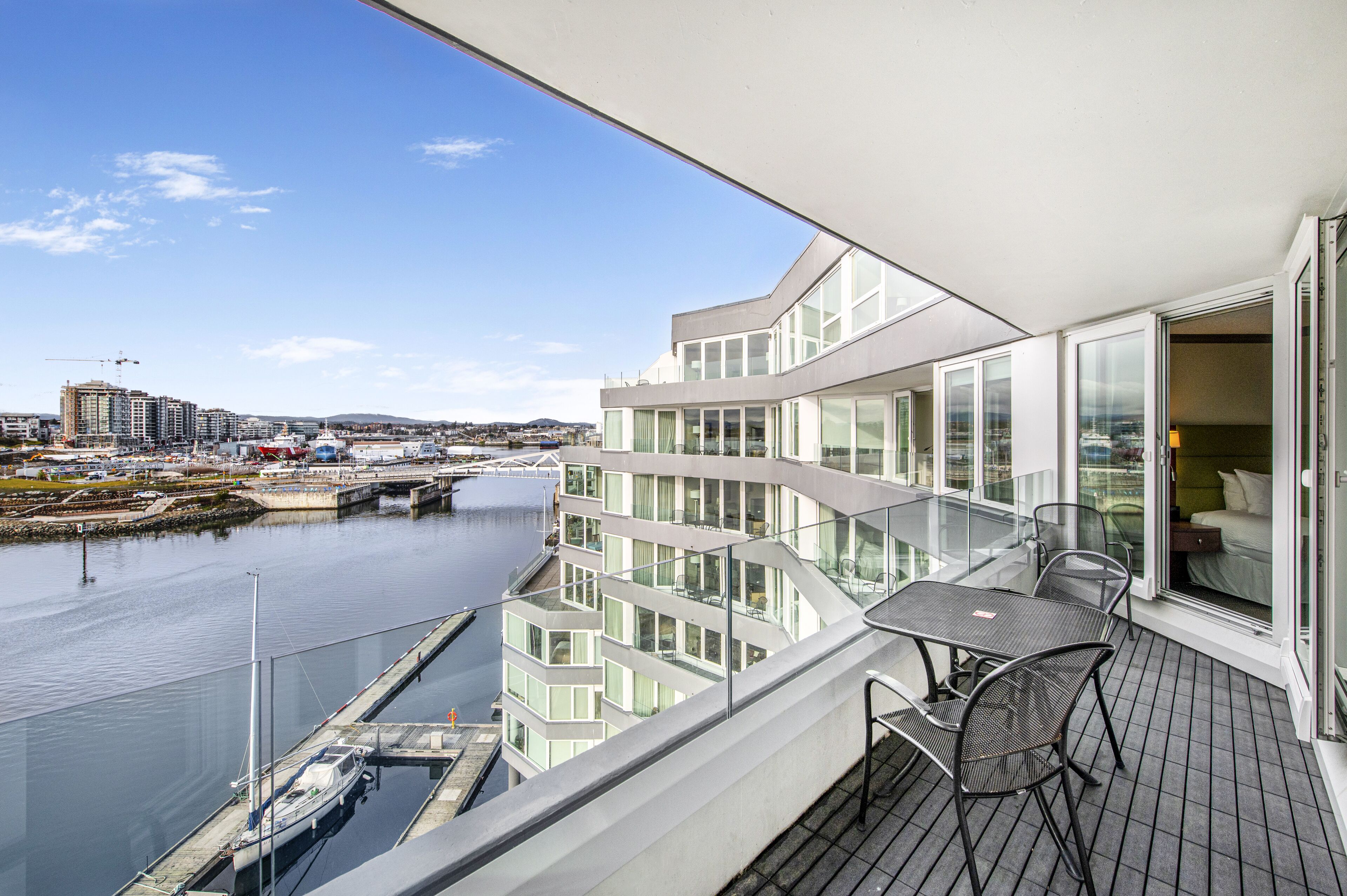 Un balcon moderne donnant sur un port de plaisance et sur le paysage urbain.