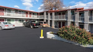 A multi-story motel with a parking lot, featuring a red and white color scheme, and a yellow bollard in the foreground. - Red Roof Inn Redding (Redding)