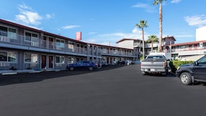 A motel with multiple-story buildings, a parking lot, and a clear blue sky. - Red Roof Inn Redding (Redding)