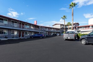 A motel with multiple-story buildings, a parking lot, and a clear blue sky. - Red Roof Inn Redding (Redding)