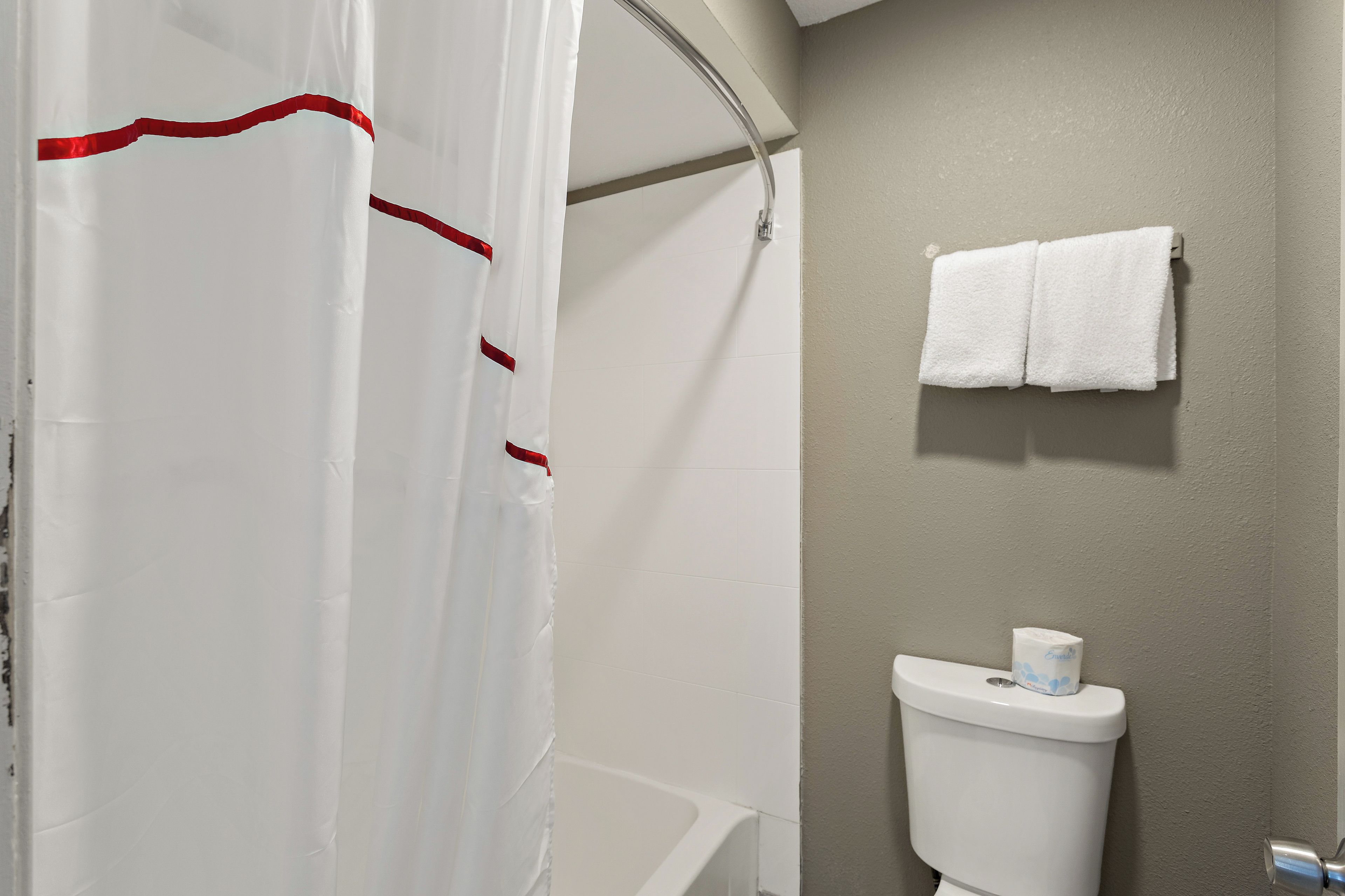 A bathroom with a shower curtain, a toilet, and a towel rack.
