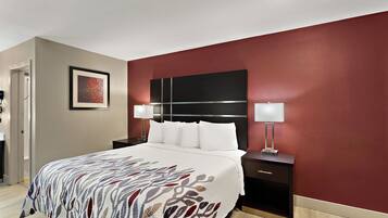 A hotel room with a bed, nightstands, a wall-mounted TV, and a door.