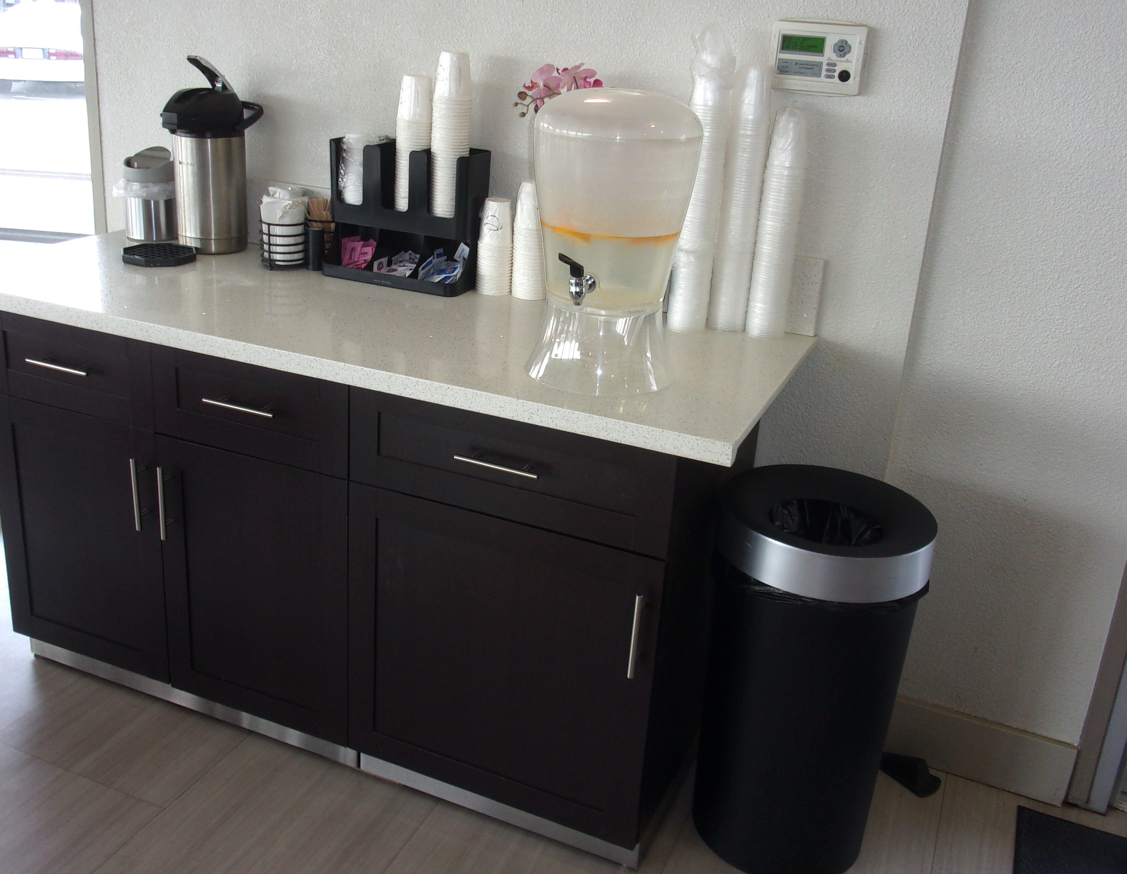 A kitchenette with a coffee machine, a water dispenser, and a trash bin.