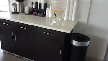 A kitchenette with a coffee machine, a water dispenser, and a trash bin.