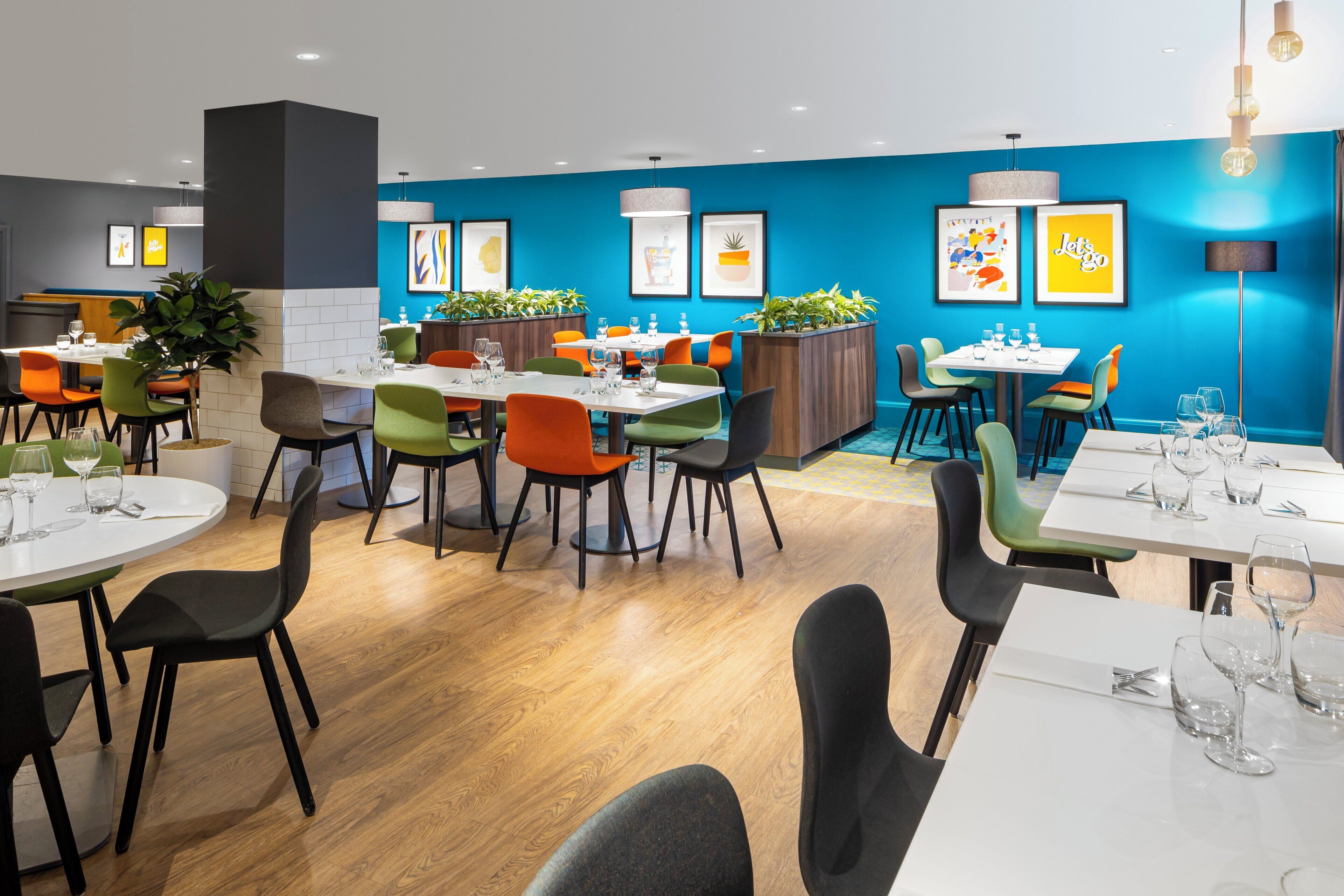 A modern restaurant with multiple dining areas, each featuring colorful chairs and tables.