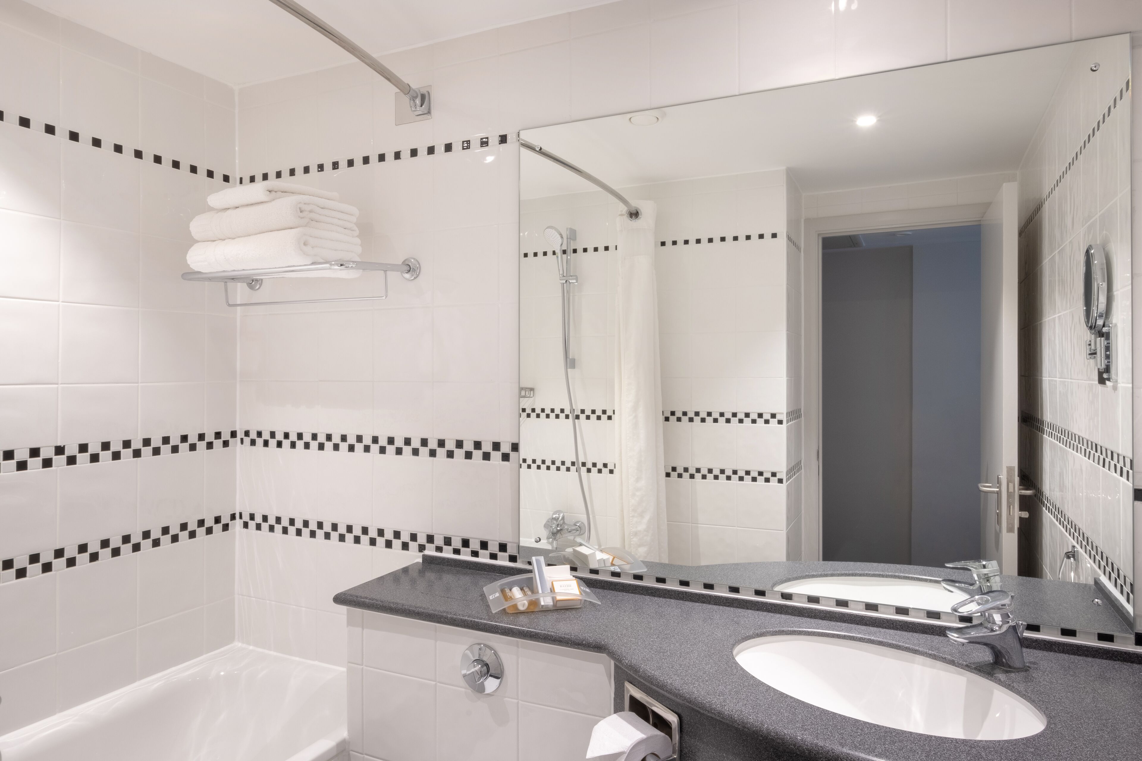 Un baño moderno con dos lavamanos, una bañera y una ducha.