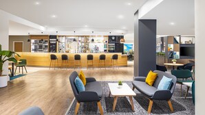 A modern lounge area with a bar, seating, and a coffee station. - Holiday Inn Leicester by IHG (Leicester)