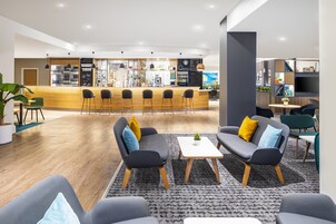 A modern lounge area with a bar, seating, and a coffee station.
