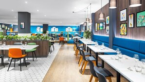 A modern restaurant with hexagonal tile flooring, wooden accents, and blue seating areas. - Holiday Inn Leicester by IHG (Leicester)