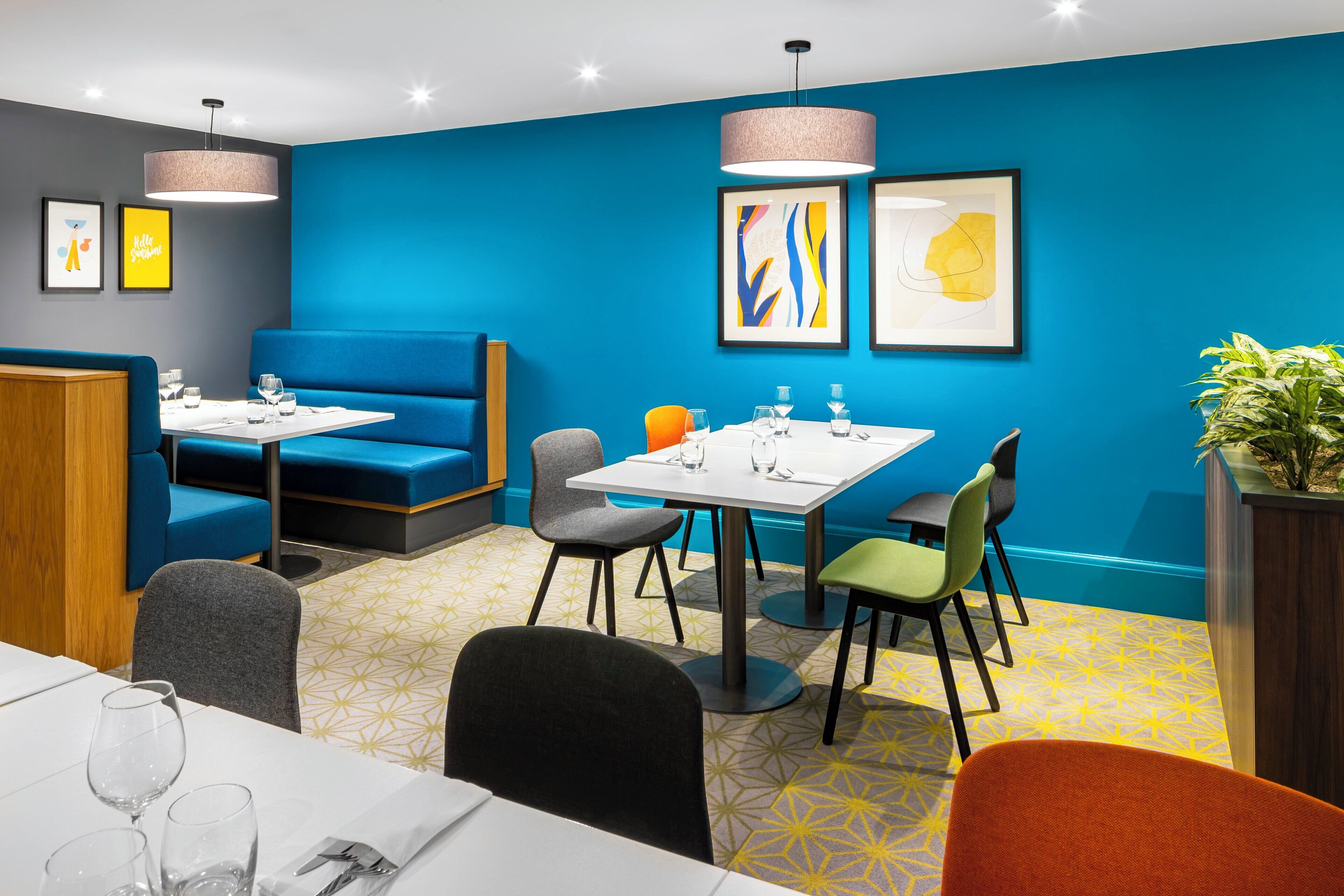 A modern dining area with blue walls, a mix of seating options including booths and tables, and contemporary artwork.