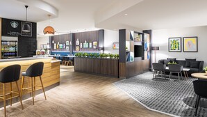 A modern hotel lobby with a bar area, seating, and a reception desk. - Holiday Inn Leicester by IHG (Leicester)