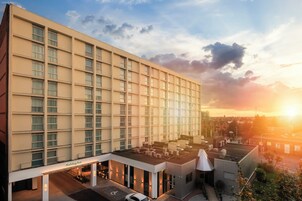 A modern hotel with a flat facade, multiple windows, and a rooftop terrace.