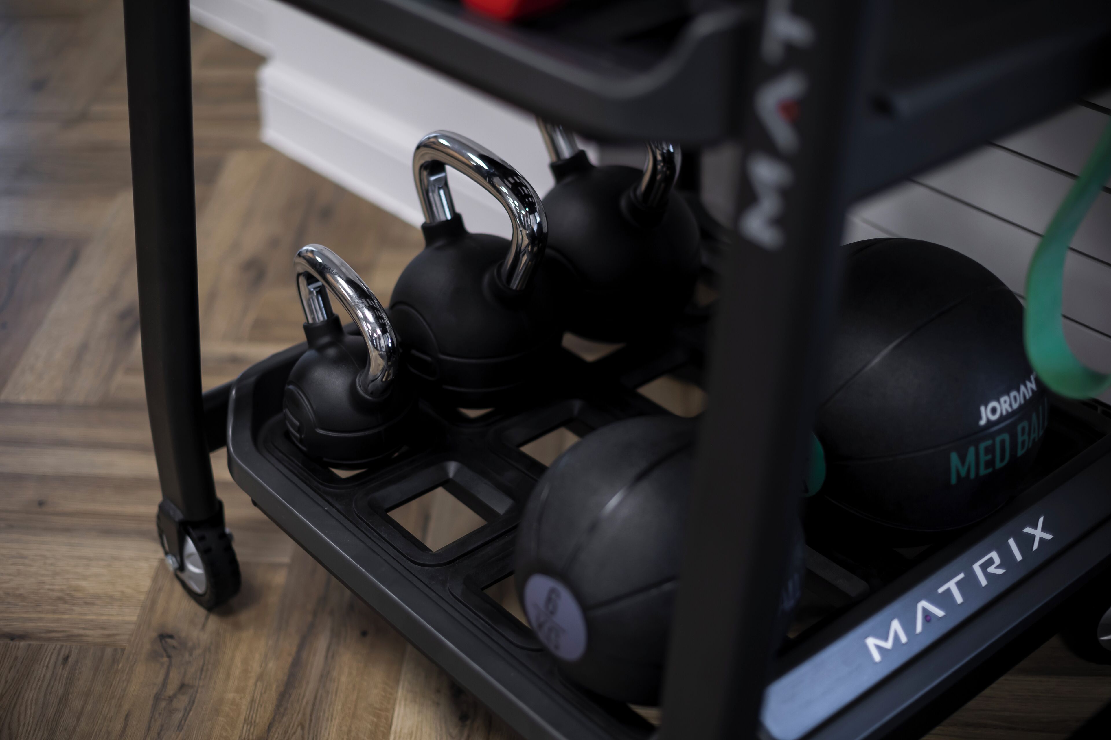 A black exercise equipment cart with kettlebells and a medicine ball.