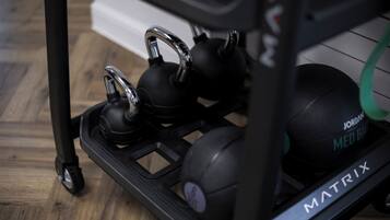 A black exercise equipment cart with kettlebells and a medicine ball.