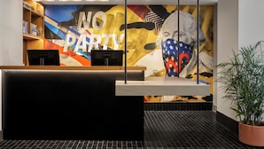 A reception area with a 'NO PARTY' sign, a large mural, and a reception desk.